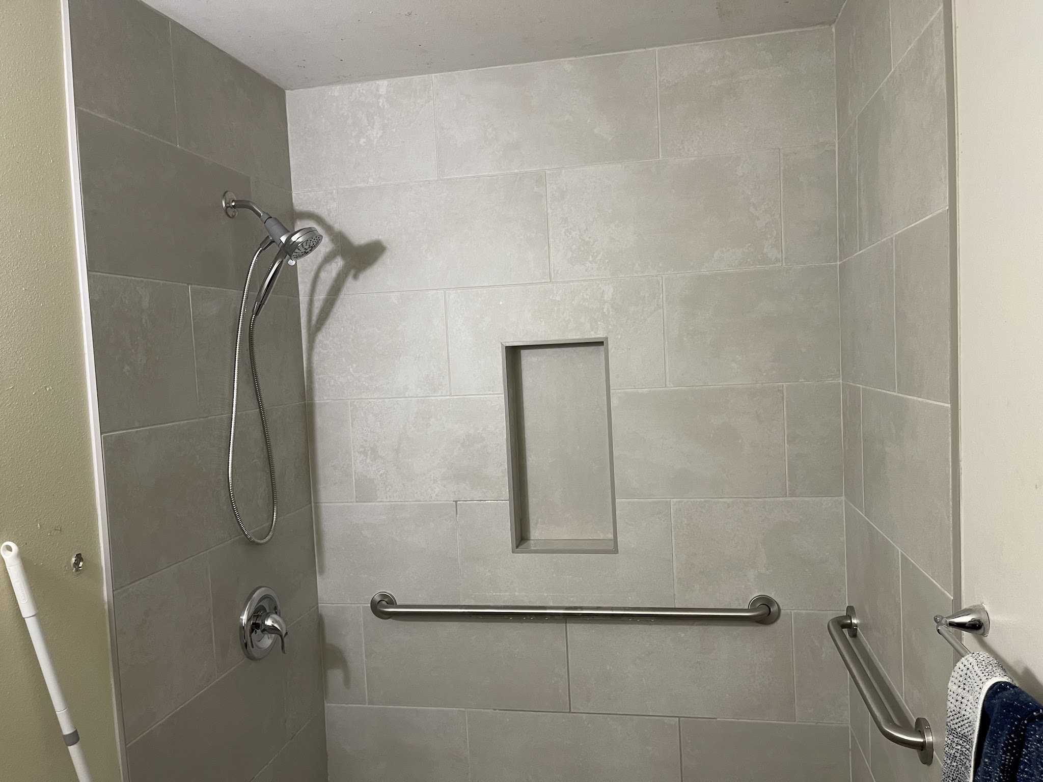 Grey tile shower remodel with grab bar and recessed niche