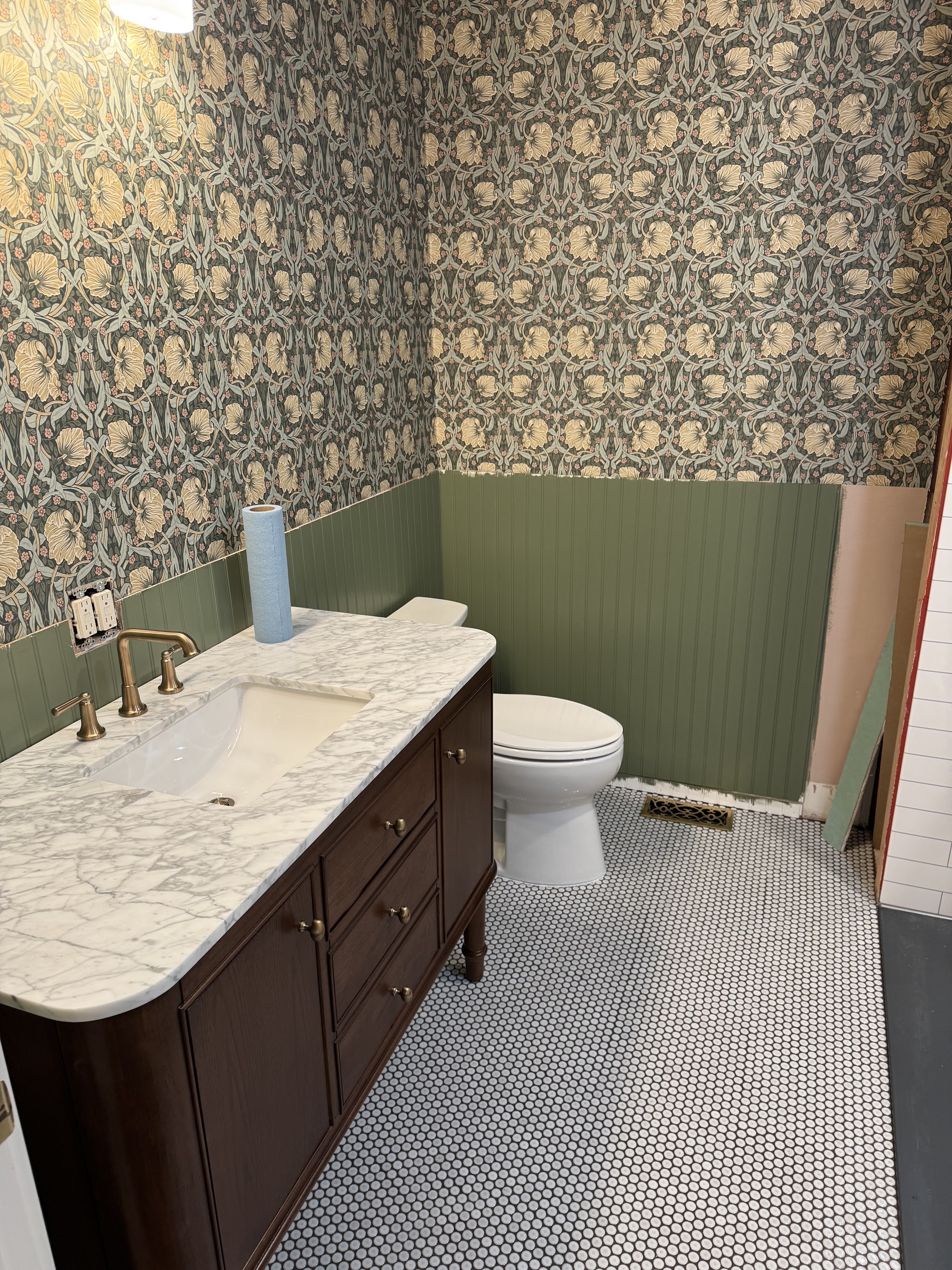 Finished powder room remodel with marble vanity and brass fixtures